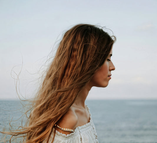 A young woman with windblown hair by the sea.